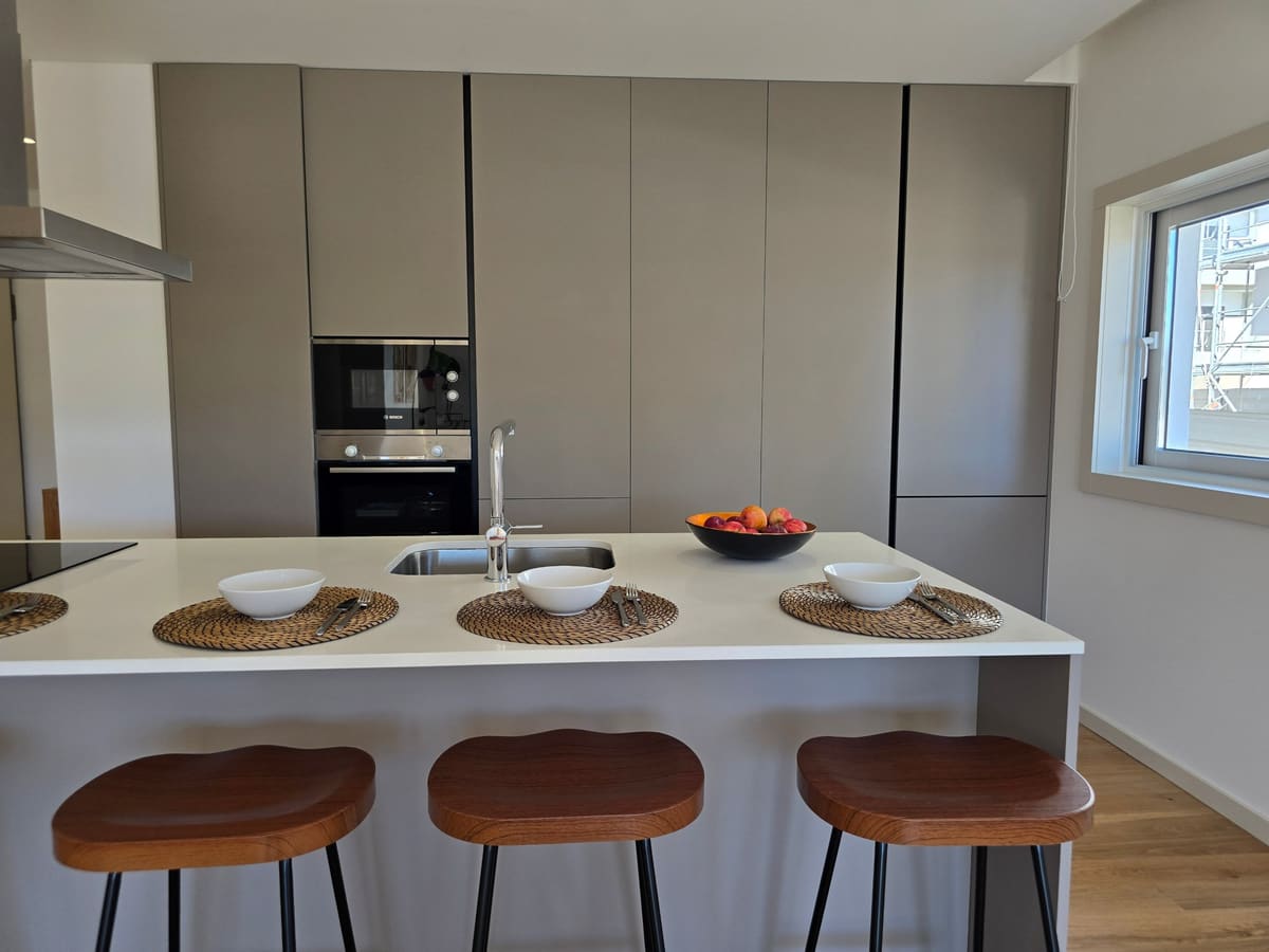 Kitchen island with three wooden stools and a wall of tall cupboards