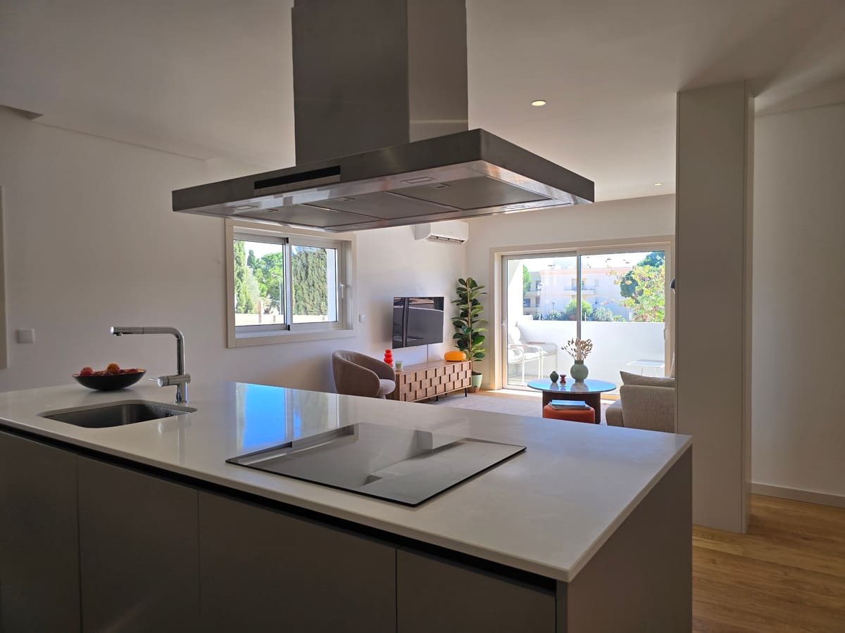 Open plan kitchen and living room at Ria Green House, with the island in front and the balcony doors beyond